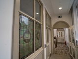 A corridor with internal stained glass windows on the left